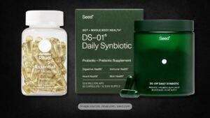 Product image of Ritual Essential for Women and Seed DS-01 Daily Synbiotic supplements displayed against a dark textured background. The Ritual bottle contains golden capsules in a transparent container with a white cap, labeled “Postnatal.” Next to it is Seed’s green glass jar and product box, promoting probiotic + prebiotic benefits for digestive, immune, heart, and skin health.